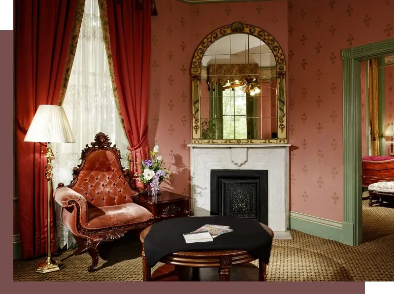 A cozy seating area with a fireplace, armchair, coffee table, and mirror.