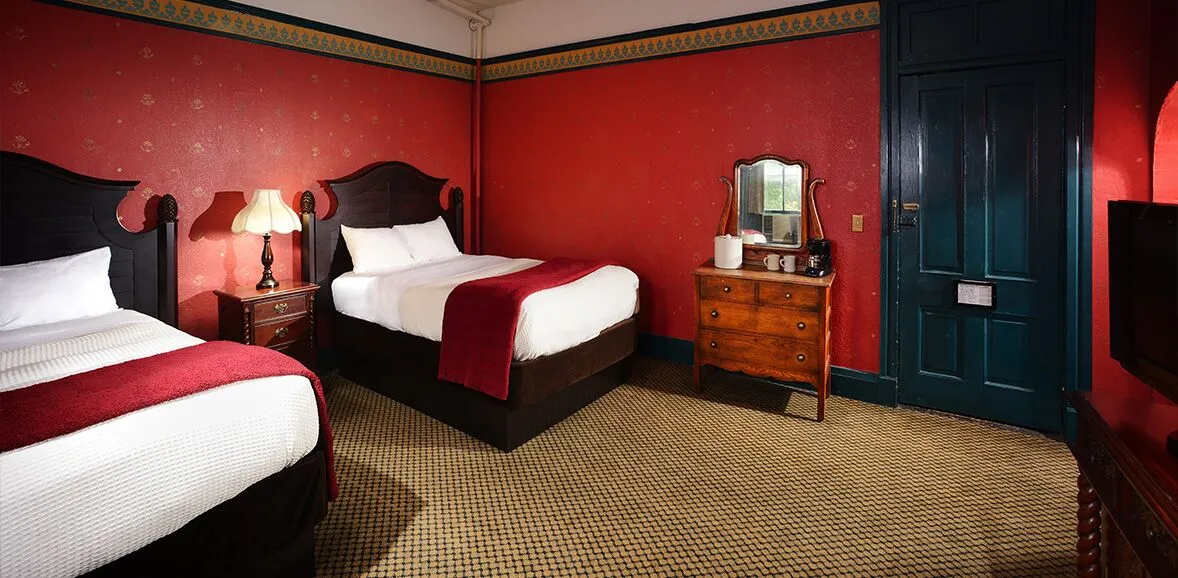A room with red wallpaper and two twin beds
