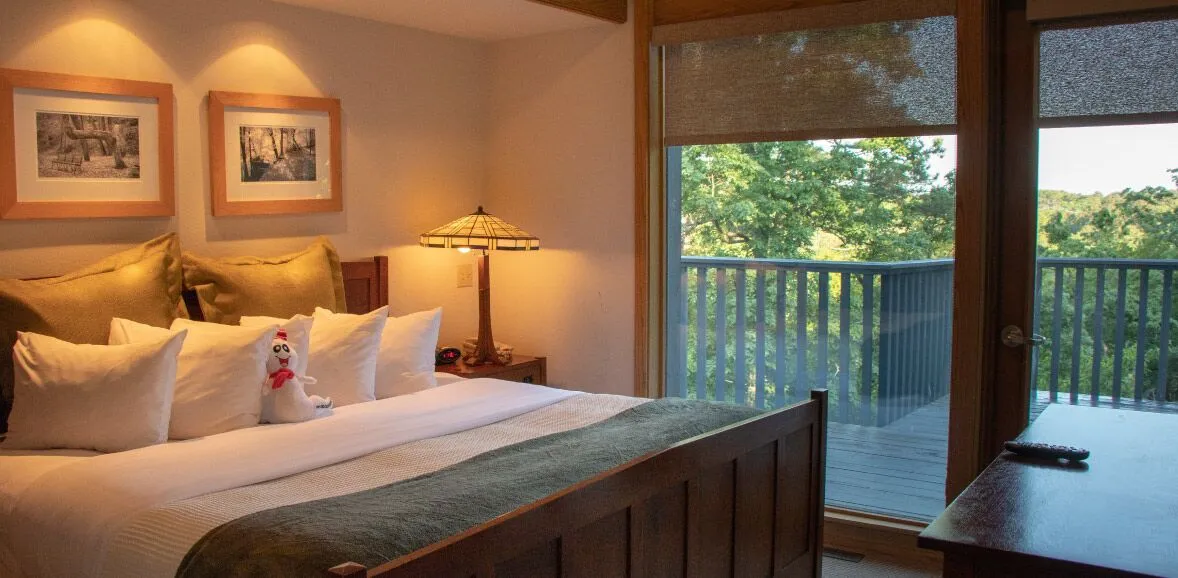A hotel room with a large bed, a balcony, and a desk.