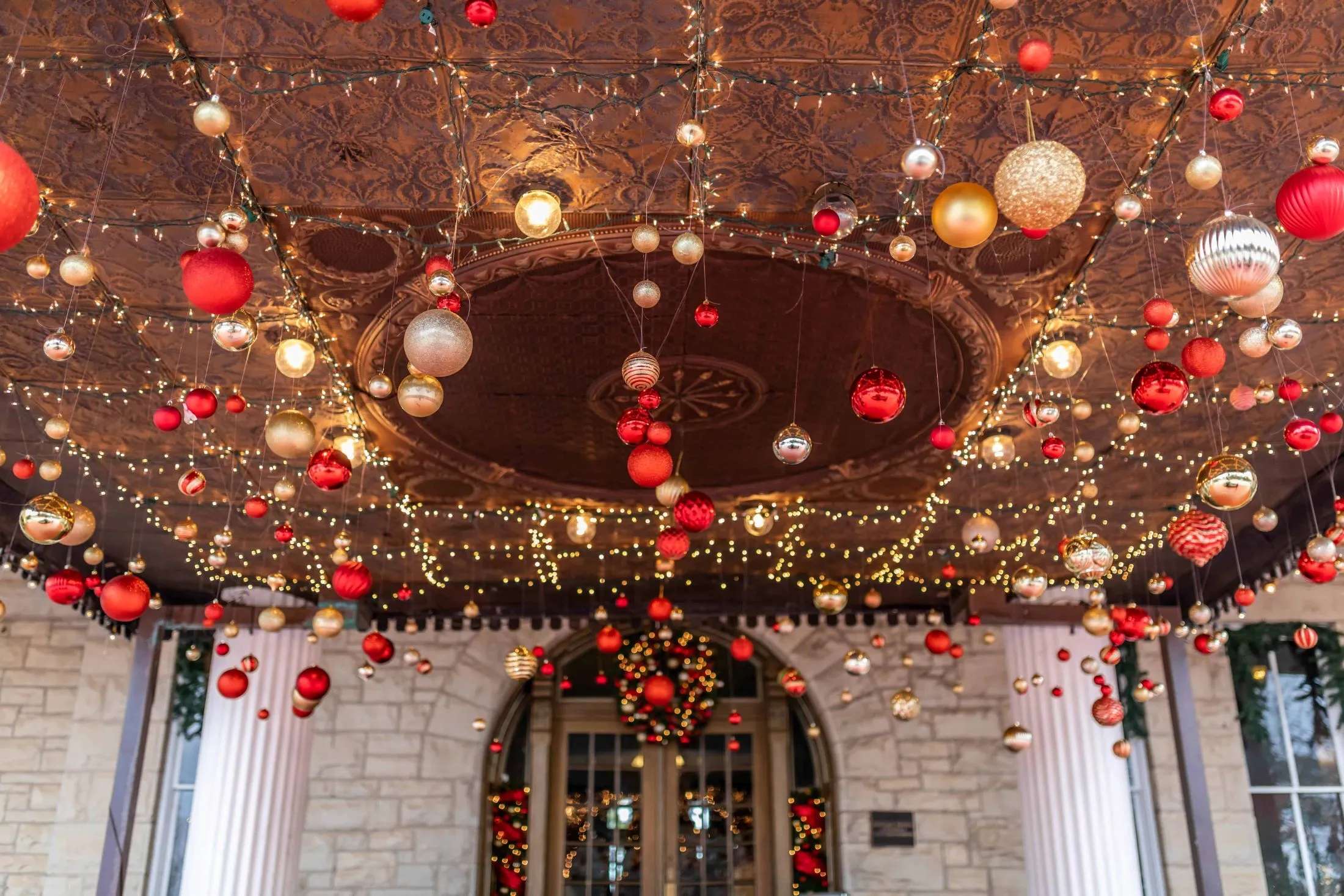 A lavishly decorated entrance with a ornate ceiling, Christmas decorations, and stone walls.