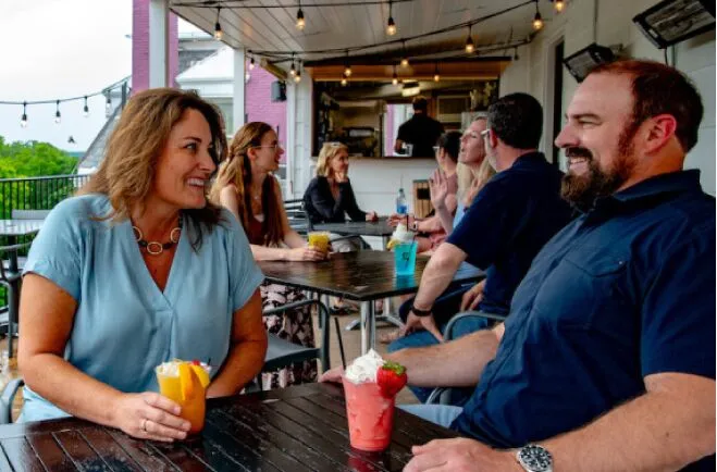 A group of people sitting at tables outside a building, enjoying drinks.