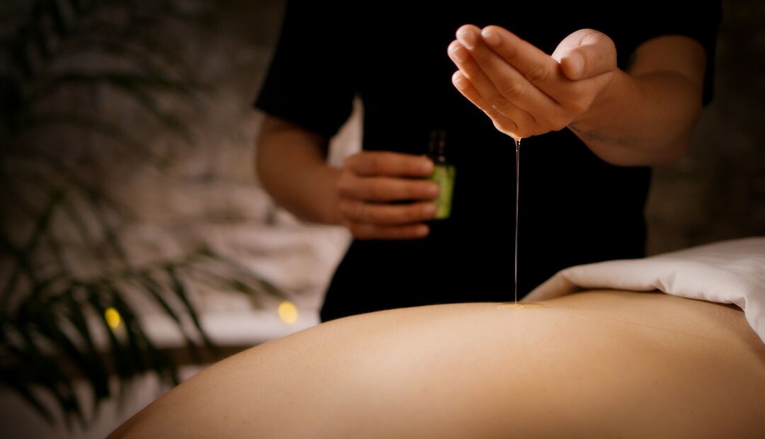 a person receiving a massage with oil being poured on their back