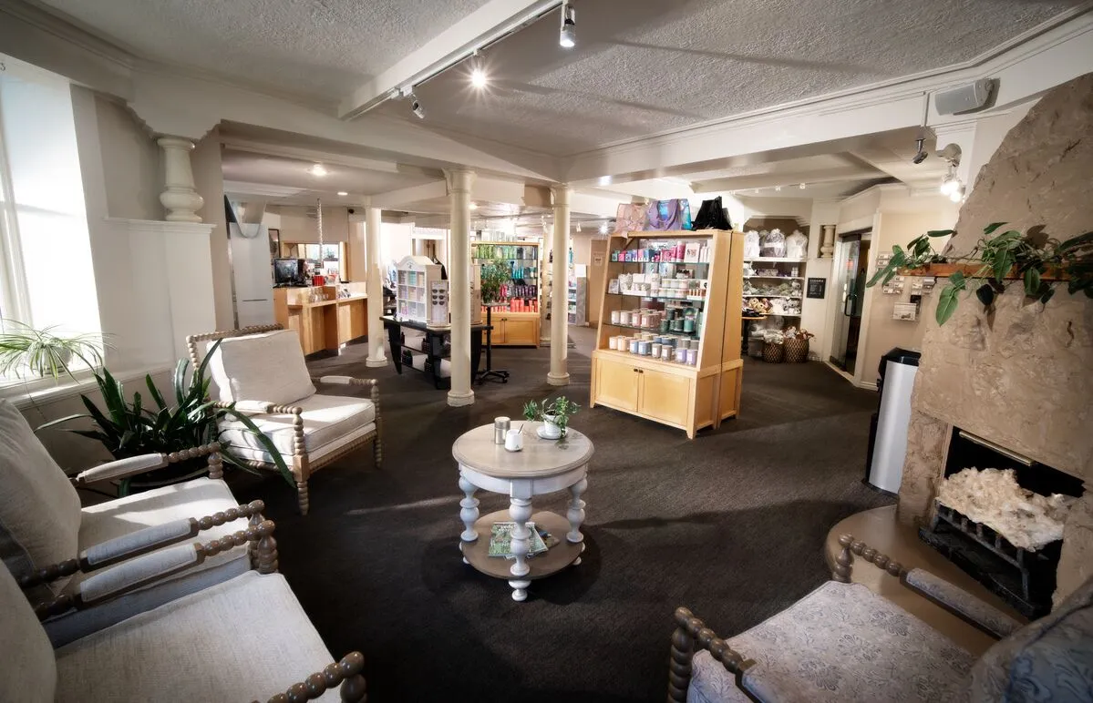 A cozy lobby with a fireplace, seating area, and shelving.
